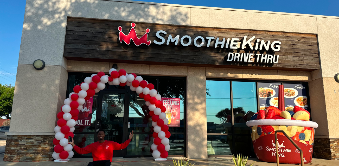 franchise store with man out front with celebratory balloons